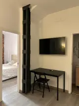 Televisor y escritorio en la zona de estar del Apartamento Exterior, con la cama visible por la puerta del dormitorio